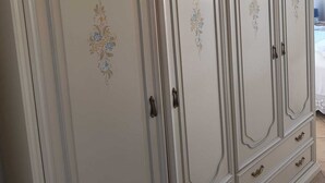 Um guarda-roupa grande e claro, com padrões florais decorativos e várias gavetas.
