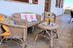 Wicker furniture, a patterned rug, and a table with a bottle and glass. - Casa MARES, an oasis of relaxation and comfort ten minutes from the center of Olbia (Olbia)