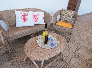 Wicker furniture with patterned cushions, a bottle of wine, and a glass on a woven table. - Casa MARES, an oasis of relaxation and comfort ten minutes from the center of Olbia (Olbia)