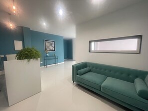 Una sala de estar moderna con un sofá color turquesa, una mesa consola blanca y un cuadro en la pared.