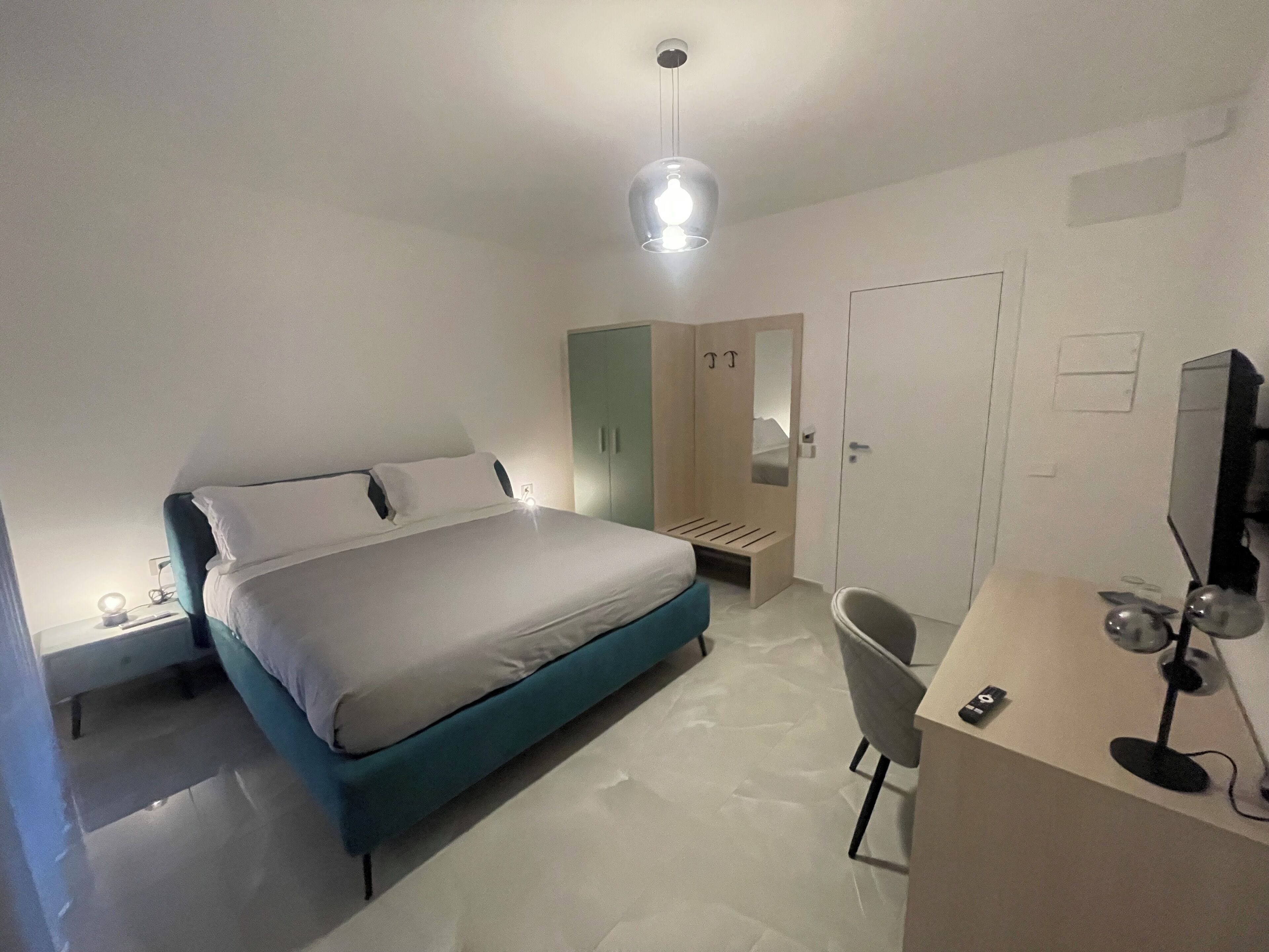 Un dormitorio moderno con cama, mesita de noche, silla, escritorio y armario.