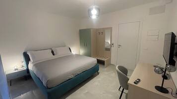 Un dormitorio moderno con cama, mesita de noche, silla, escritorio y armario.