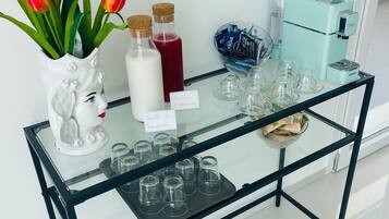 Una mesa con cubierta de vidrio, tulipanes, botellas y vasos.