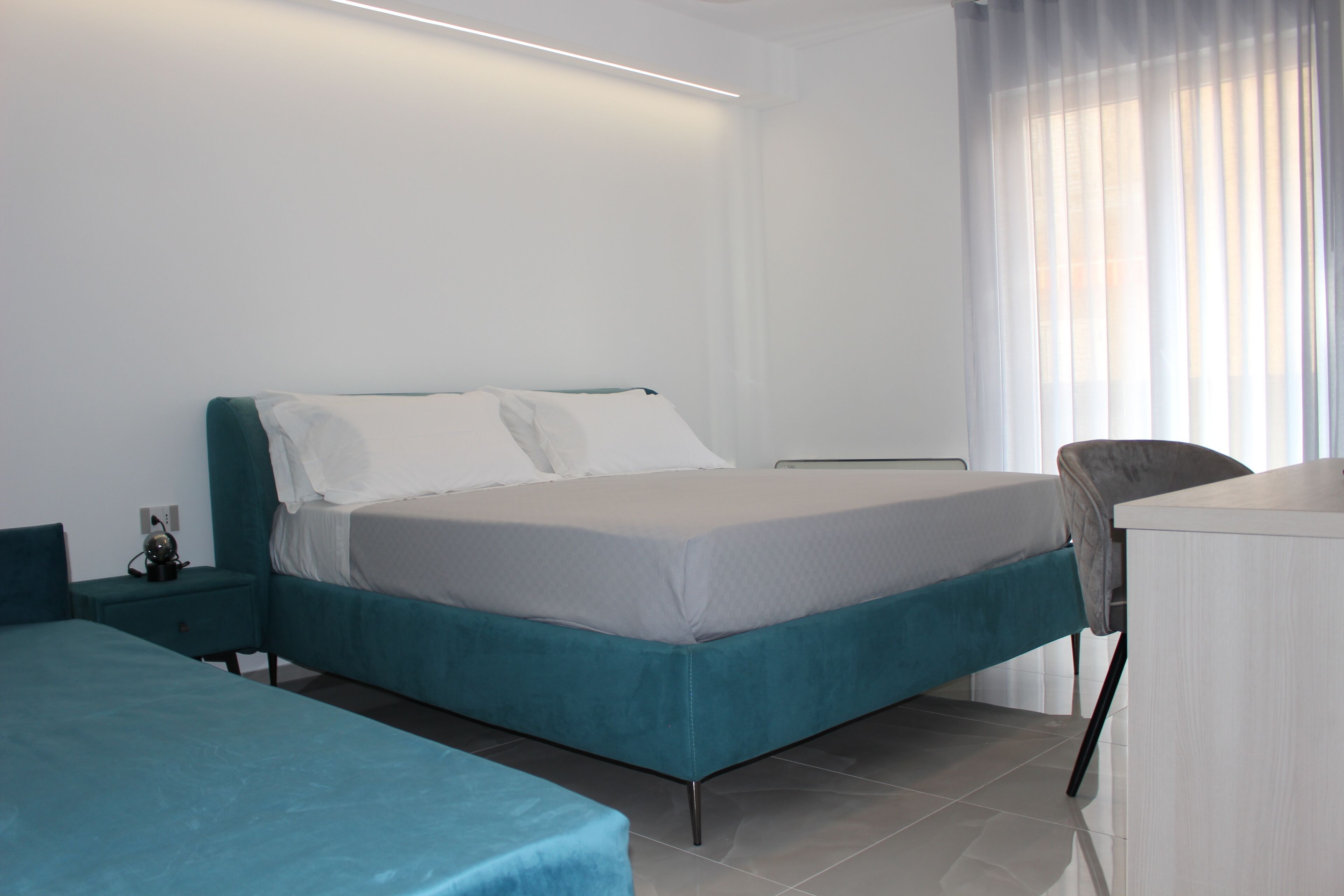Quarto de hotel moderno com uma cama de solteiro, uma escrivaninha e uma cadeira.