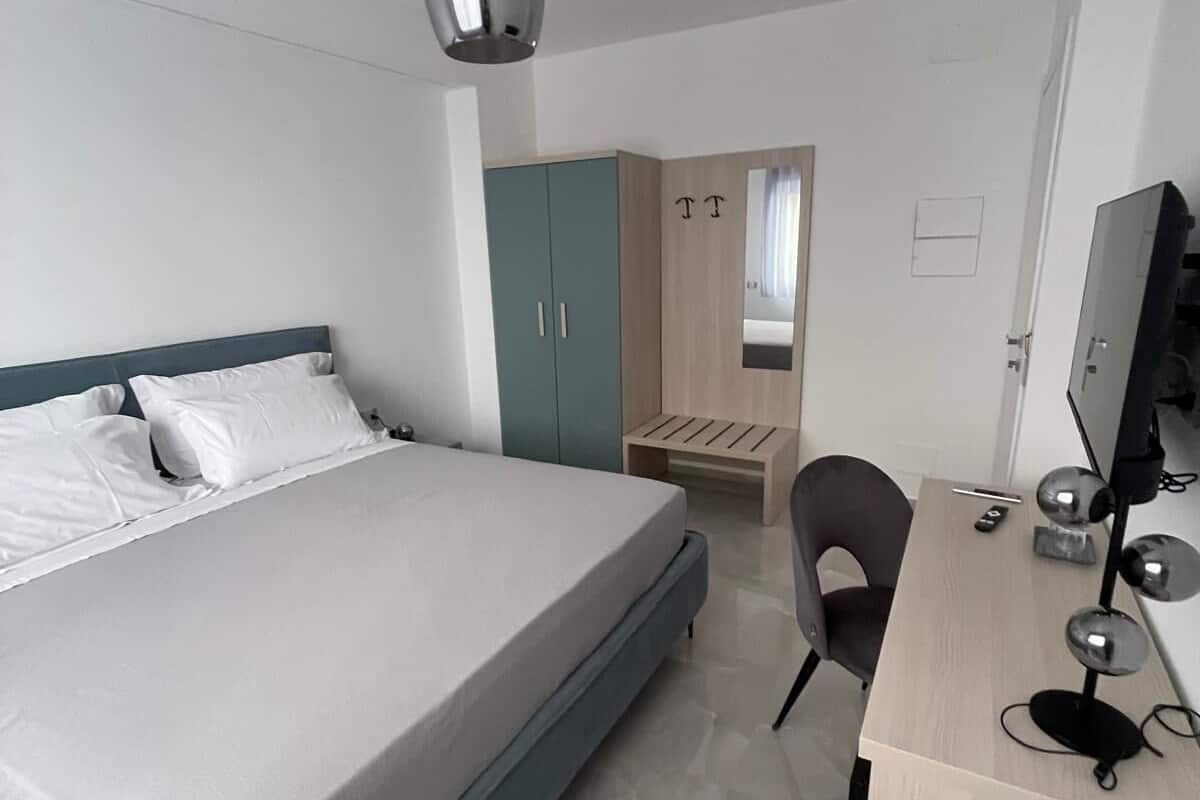 Un dormitorio moderno con cama, escritorio, silla, armario y espejo.