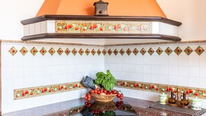 Una cocina con salpicadero de azulejos, una frutera en el centro y una campana extractora.