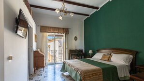 Un dormitorio con cama, escritorio, silla, televisión y ventana con vistas al exterior.