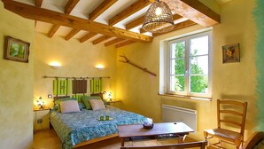 Une chambre à coucher avec un lit, une table en bois, une chaise et une fenêtre donnant sur un paysage agréable.
