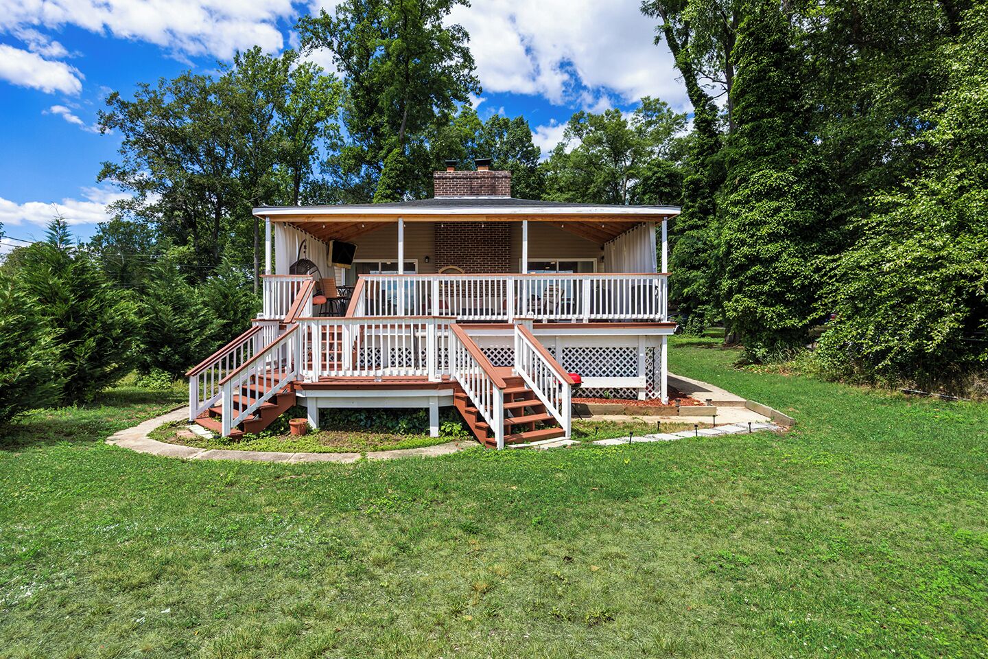 Une maison à deux étages avec une terrasse, un escalier et une cheminée.