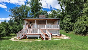 Une maison à deux étages avec une terrasse, un escalier et une cheminée.