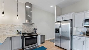 A modern kitchen with stainless steel appliances, a gas stove, white cabinetry, and a blue rug.