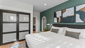 A modern bedroom with a large bed, a sliding glass door, and abstract wall art.
