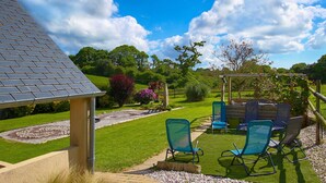 Un jardin agrémenté d’une pergola, d’un espace salon extérieur et d’une pelouse bien entretenue.