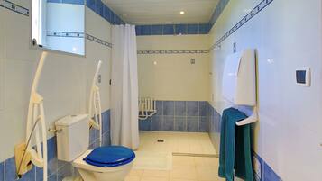 A bathroom with a toilet, shower, and a towel rack.