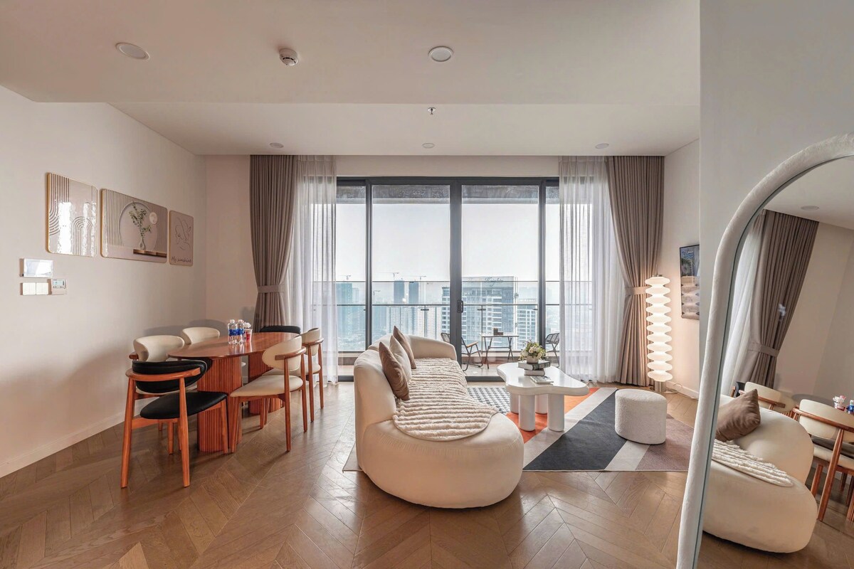 Una sala de estar moderna con sofá, mesa de comedor, sillas y un ventanal con vista a la ciudad.