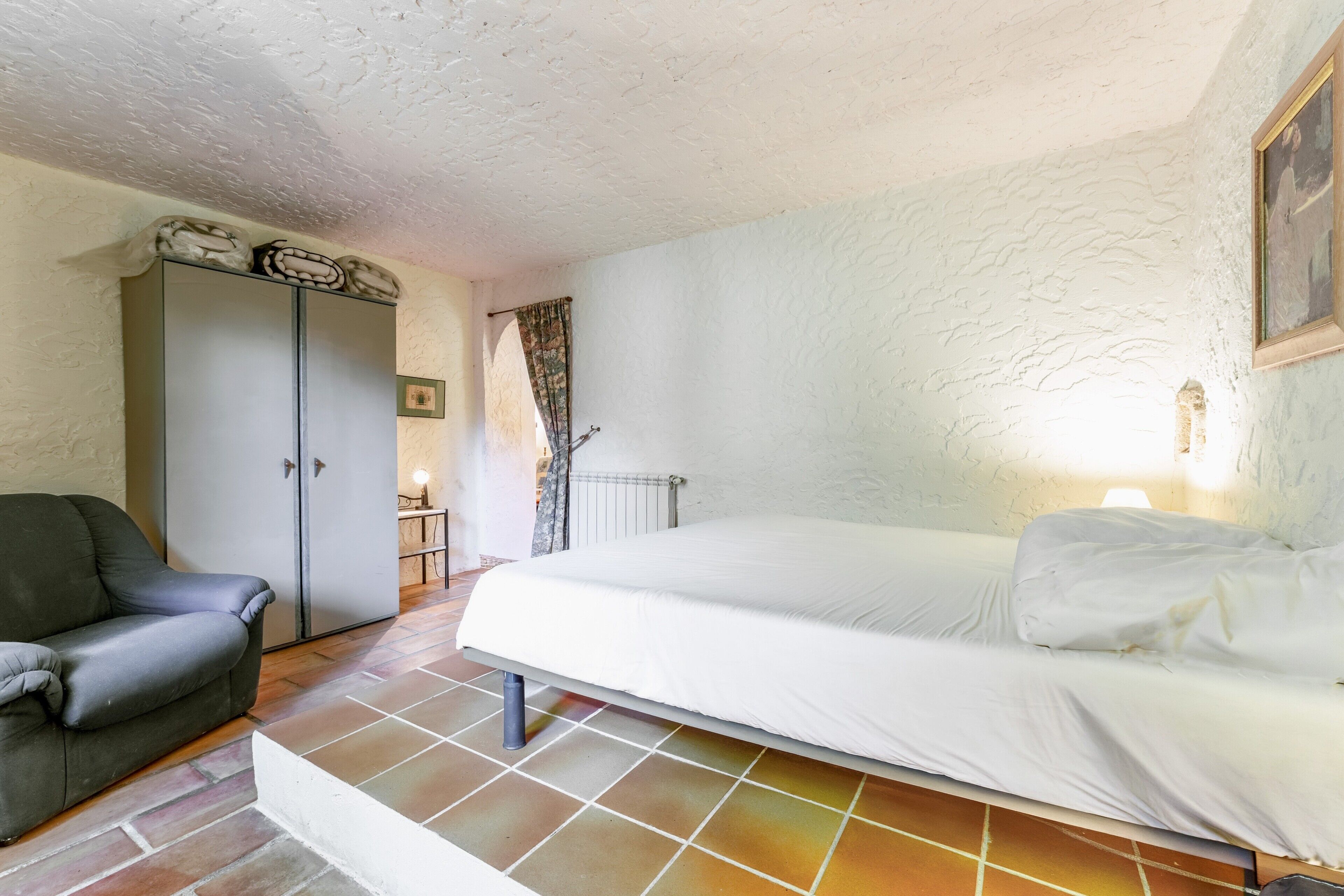 Une pièce comprenant un lit, un canapé, une armoire et un radiateur.