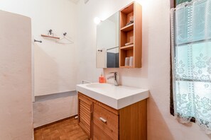 Une salle de bain avec un meuble-lavabo en bois, un miroir, un évier et un espace douche.