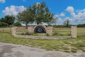Un arco in pietra con l'iscrizione 'HILL VALLEY ESTATES' e un'area curata con prato e alberi.