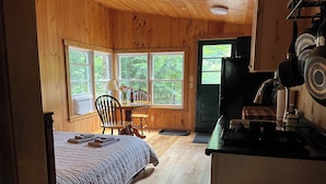 L’intérieur d’une cabane en bois comprend un lit, une table à manger, des chaises et un coin cuisine.