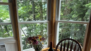 Une table en bois, ornée d’un vase de fleurs, d’une bouteille de vin et d’un menu.