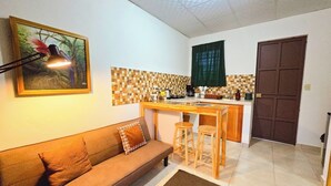 A compact living space with a sofa, a small kitchen area, and a door.