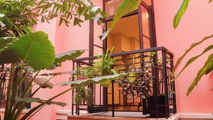 Un balcon agrémenté de plantes en pot, une fenêtre et une porte donnant sur un espace intérieur.