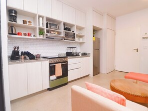 Une cuisine moderne avec des meubles blancs, une cuisinière, un four à micro-ondes et un réfrigérateur.