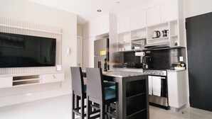 A modern kitchen with built-in appliances, a dining area with chairs, and a flat-screen TV mounted on the wall. - The Glow Stay | Elegant and Modern | @SantaAna (Panama City)