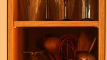A wooden cabinet with shelves containing glassware and a jar of Jamaica Blue Mountain coffee.