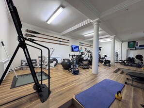 A gym with exercise equipment, a television, and a wooden floor. - The Gardener's Cottage, Low Hall (Scarborough)