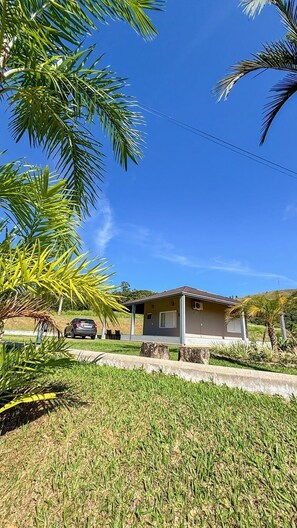 A single-story house with a small porch, surrounded by well-maintained grass and palm trees. - Hotel O Recanto Serra Negra (Serra Negra)