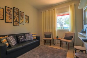 A living room with a black sofa, two armchairs, a small table, and a window with curtains. - Hotel O Recanto Serra Negra (Serra Negra)