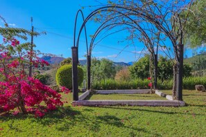 A garden with a gazebo, a small pond, and a pink flowering tree. - Hotel O Recanto Serra Negra (Serra Negra)