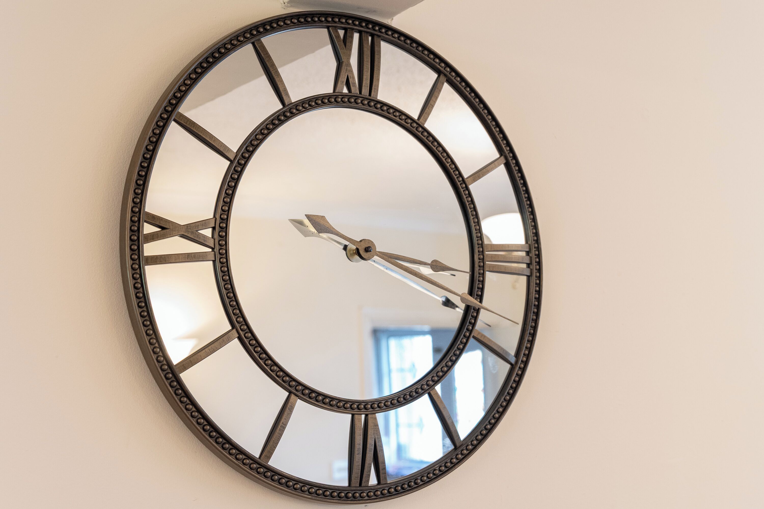 A wall-mounted clock with Roman numerals and a decorative frame.