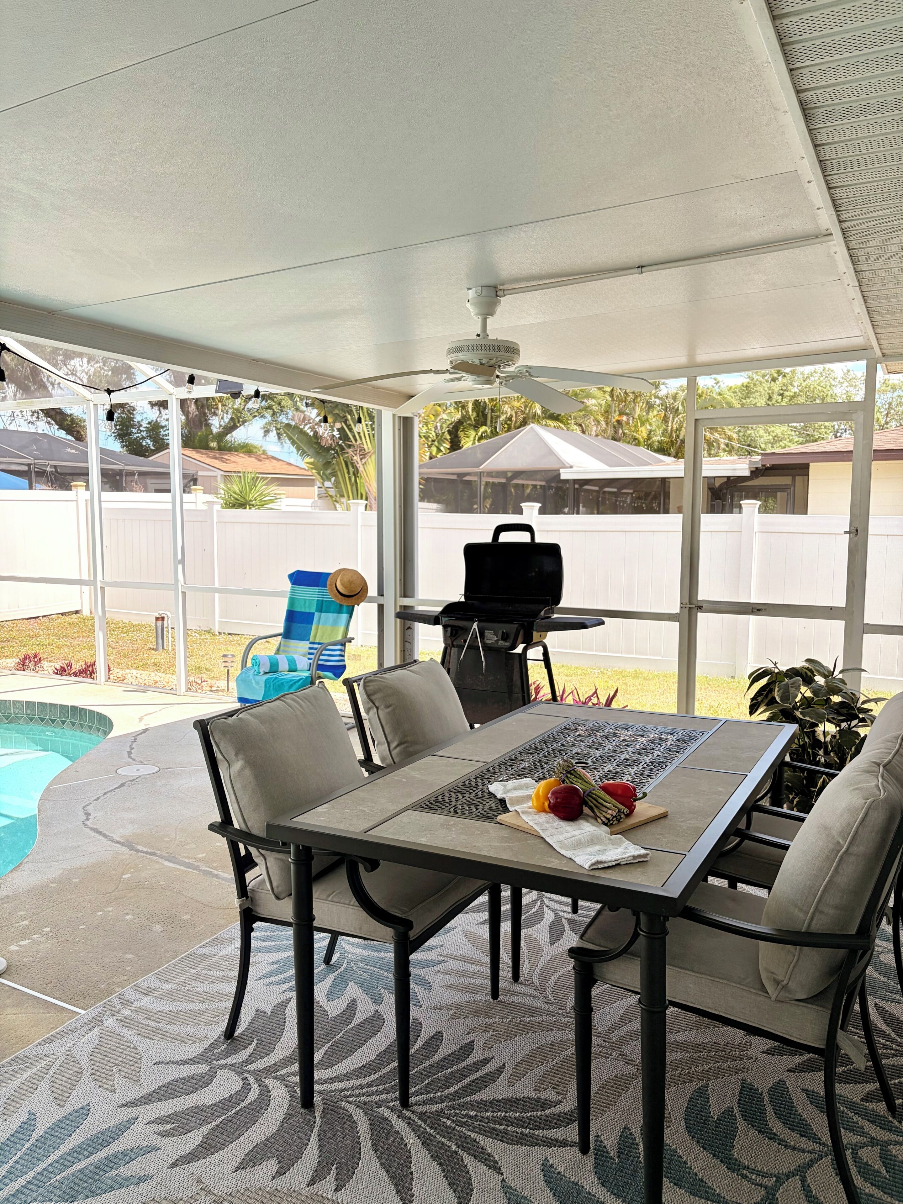 Un patio couvert avec une piscine, un barbecue et du mobilier d’extérieur.