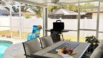 Un patio couvert avec une piscine, un barbecue et du mobilier d’extérieur.