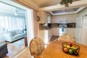 Cocina moderna con gabinetes blancos, un microondas y un refrigerador.