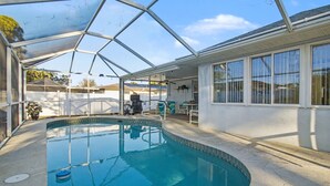Una piscina techada con techo de vidrio, un área de barbacoa y un patio con sillas y mesas.