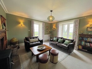 A living room with two leather sofas, a coffee table, a bookshelf, and a globe on a stand.
