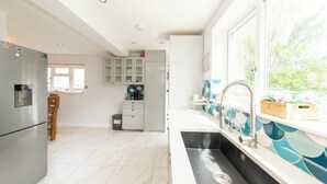 A modern kitchen with a large window, a built-in sink, and a refrigerator. - Modern House with AC 4 Parking & Transport Links - Pass the Keys (Reading)