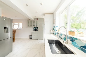 Een moderne keuken met een groot raam, een inbouwspoelbak en een koelkast.