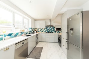 Een moderne keuken met een roestvrijstalen koelkast, een ingebouwde vaatwasser en een betegelde achterwand.