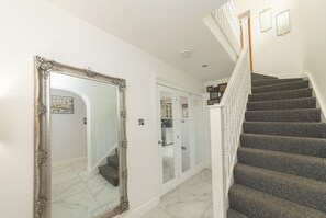 A staircase with a handrail, a large ornate mirror, and a door with a glass panel. - Modern House with AC 4 Parking & Transport Links - Pass the Keys (Reading)