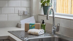 A kitchen sink with a faucet, a towel, a soap dispenser, and a card on the counter. - Beautiful, newly refurbished Victorian townhouse - Pass the Keys (Windsor)