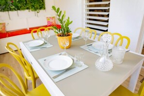 A dining table set with plates, cutlery, and glasses, surrounded by yellow chairs. - Aiméelie Tropical Lodge: Pool & Close to Rivers (Lamentin)