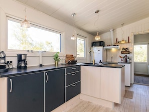 A modern kitchen with a central island, black cabinetry, and pendant lighting.