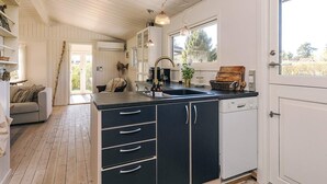 A kitchen with a black countertop, white cabinets, a sink, and a window. - 4 Star Holiday Home in Graested (Graested)