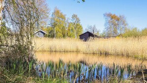 A serene lakeside setting with two cabins surrounded by tall grasses and trees. - 4 Star Holiday Home in Graested (Graested)