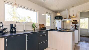Een moderne keuken met een centraal eiland, inbouwapparatuur en hangende lampen.