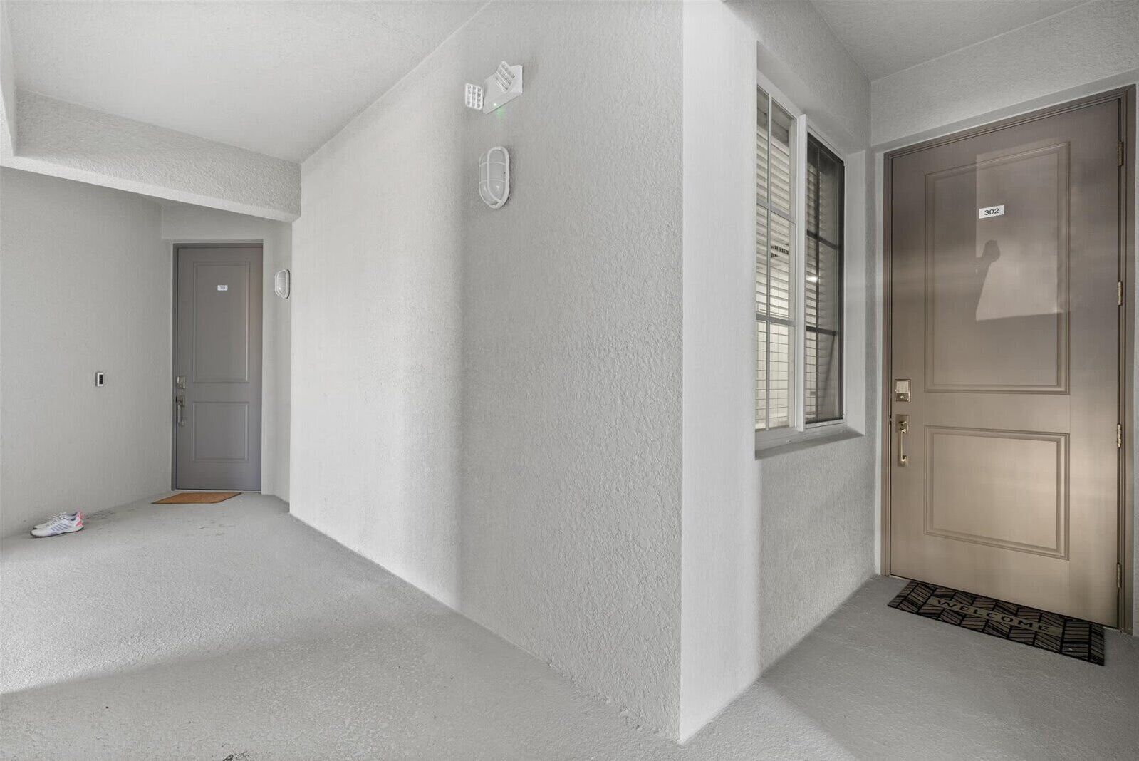 A hallway with a door marked '302,' a window with blinds, and a doorbell.